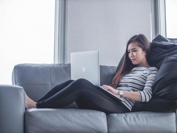 Women using her laptop while sitting on gray couch